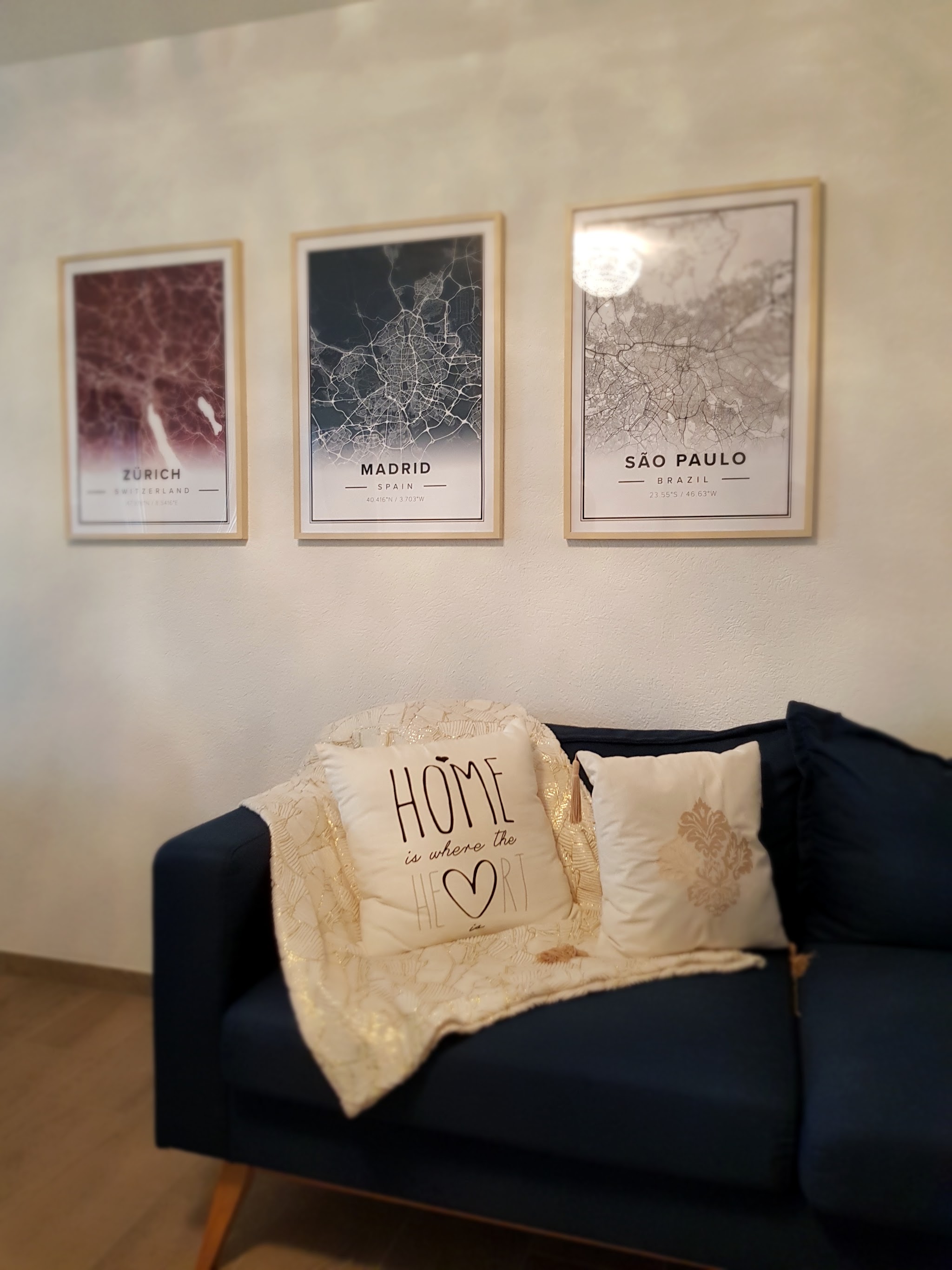 Drei gerahmte Stadtkarten über dem Sofa aufgehängt